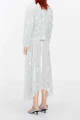 Falda midi color gris plata de terciopelo con textura, cierre frontal con botones y lazo en la cintura.