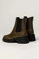 Bota tipo Chelsea de cuero color verde oliva, con paneles laterales elásticos negros y suela track de goma negra con taco cuadrado.