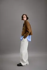 Chaqueta corta de efecto ante en color marrón, con cuello solapa, manga larga y trabillas en los hombros. Presenta cierre frontal con botones y bolsillos delanteros de doble vivo.