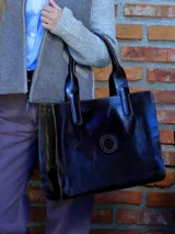 Cartera tipo tote de cuero vacuno en color marrón oscuro, con diseño estructurado, costuras a la vista y logo grabado en el centro. Incluye doble asa de hombro y compartimento interno removible.