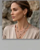 Set de joyería compuesto por un collar de tres cadenas finas con dijes de esferas metálicas y un par de aros colgantes con diseño de esfera. Fabricado en acero italiano.