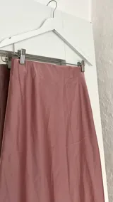 Pollera midi de seda color rosa, con cintura elástica.