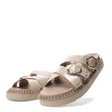 Sandalias planas Miss Carol modelo Zelv, color beige, con tiras anchas decoradas con hebillas metálicas doradas y tachas, sobre suela de plataforma baja con costuras visibles.