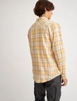 Camisa de manga larga a cuadros amarillos, blancos y grises, con bolsillo en el pecho y botones de pasta.