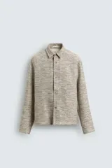 Sobrecamisa de hombre con corte relajado, confeccionada en tejido texturizado jaspeado en tonos beige y negro. Presenta cuello solapa, manga larga con puño de botón y cierre frontal de botonadura.
