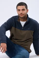 Buzo de polar texturado con diseño bicolor en azul marino y marrón, cuello alto con medio cierre y bolsillos laterales.