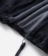 Campera tipo bomber confeccionada en tejido de jean, con cierre frontal de cremallera, capucha ajustable con cordones y bolsillos frontales. Presenta puños y cintura elásticos, ofreciendo un ajuste cómodo y un estilo urbano.