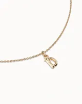 Charm unisex con forma de letra "D" con acabado dorado, inspirado en el diseño de clavo de UNOde50.