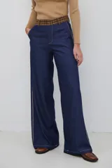Pantalon de corte recto y pierna ancha, confeccionado en tela tipo denim color azul oscuro, con costuras a contratono y detalle de abertura lateral en el ruedo.