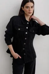 Chaqueta de denim negro, de corte entallado en la cintura, con cuello clásico, cierre frontal de botones metálicos y bolsillos con solapa en el pecho.