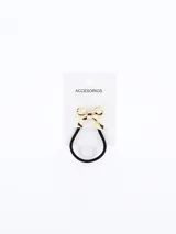 Colero (liga para el pelo) negro con un dije metálico en forma de moña dorada.