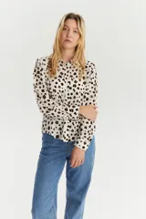 Camisa de manga larga con cuello clásico y estampado de manchas marrones sobre fondo blanco.