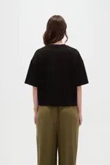 Remera blanca de manga corta, con cuello redondo a la base y diseño holgado.