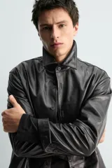 Sobrecamisa de corte regular confeccionada en piel napa negra, con cuello solapa, cierre frontal de botones y mangas largas con puños abotonados.
