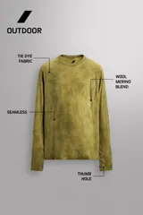 Camiseta térmica de manga larga ranglán, cuello redondo, color verde oliva con efecto tie-dye o jaspeado. Presenta tejido con lana, alta elasticidad y ajuste al cuerpo, con estructuras combinadas para facilitar la transpiración y sin costuras.