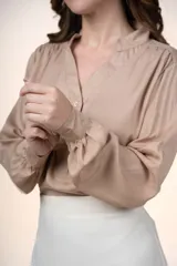 Blusa de tencel color beige con cuello mao, escote en V con botones frontales y mangas largas abullonadas.