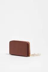 Billetera Bimba y Lola color marrón, de estructura rígida en piel vacuna, con cierre de cremallera y tirador de cordón en color crudo. Incluye logo de la marca estampado en dorado en el frente.