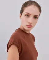 Camiseta ajustada color marrón con mangas cortas y terminaciones con volados delicados en cuello, mangas y dobladillo.