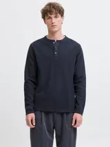 Remera de manga larga con cuello henley y cierre frontal con tres botones. Confeccionada en algodón orgánico, presenta un corte regular y diseño liso.