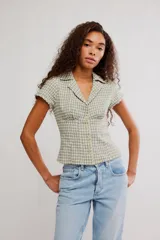 Camisa de mezcla de algodón y lino, de cuerpo entallado, con diseño a cuadros en tonos verde y beige. Presenta escote en V con cuello de solapa, mangas cortas y cierre frontal con botones.