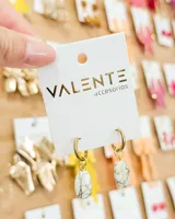 Aros tipo argolla de acero dorado con dije colgante de piedra blanca con vetas doradas.