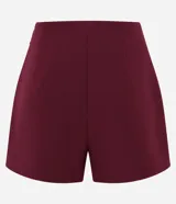 Short pollera de sastrería marca Cortelle, color bordó, confeccionado en crepé. Presenta sobreposición frontal efecto pollera con pliegues y detalle de cadena metálica decorativa en el lateral.