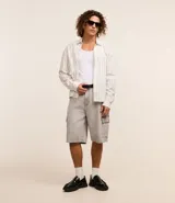 Bermuda de hombre en denim de algodón, modelo cargo, corte baggy y tiro medio. Presenta bolsillos laterales tipo cargo y cierre tradicional con botón y cremallera.