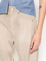 Pantalón ancho de cuero ovino color beige, con recortes verticales y horizontales, bolsillos delanteros tipo jean y bolsillos traseros tipo parche.
