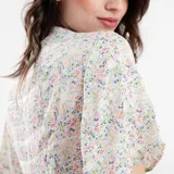 Mono corto con estampado floral celeste, escote cruzado, mangas cortas con volados y lazo en la cintura.