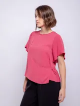 Top rosado de mangas cortas con volados, cuello redondo y detalle diagonal en el frente.
