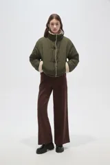 Campera puffer de poliamida color verde militar, con interior y detalles en corderito color crema. Presenta cuello alto, cierre frontal con botones a presión y mangas largas.