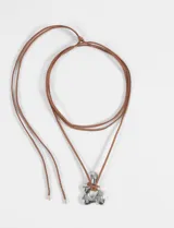 Collar con cordón marrón ajustable y dije de acero plateado con forma de flor irregular.