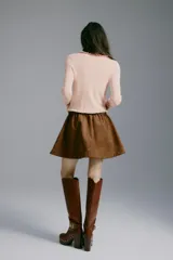 Saco de punto acanalado fino de mezcla de viscosa, color rosado, con ajuste entallado, cuello redondo y cierre frontal de botones. Presenta delicados ribetes con volados en el escote, la tapeta y el bajo.
