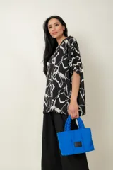 Cartera color salmón con diseño acolchado, forma rectangular y asas cortas trenzadas. Tiene un parche rectangular de cuero sintético negro en el centro.