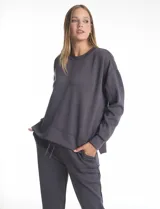 Buzo deportivo de cuello redondo, con hombros caídos y mangas largas con puños. Presenta costuras decorativas tipo pespunte en la parte frontal y en las mangas, con un diseño de ruedo recto y tajos laterales.