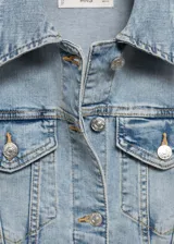 Chaqueta de jean estilo vaquero, color celeste claro, con cuello clásico, cierre frontal de botones metálicos, bolsillos con solapa en el pecho y bolsillos laterales.