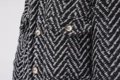 Tapado largo estilo chemise confeccionado en lana italiana tejida con patrón de espiga en color negro y gris. Presenta cierre frontal con botones y bolsillos con solapa.