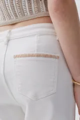 Jean blanco de tiro medio-alto y pierna acampanada estilo Oxford, con pespuntes en zigzag en los bolsillos traseros y terminación desflecada.