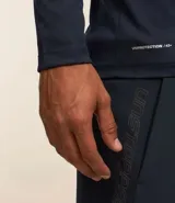 Remera deportiva de manga larga con cuello redondo, confeccionada en tejido de malla de poliéster. Presenta un diseño con estampado geométrico tipo delta punteado en el pecho.