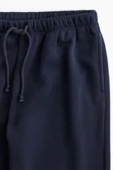 Pantalón tipo jogger de felpa color azul marino, con cintura elástica y cordón de ajuste. Presenta un corte amplio y holgado con bolsillos laterales discretos.