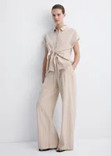 Camisa de lino y algodón color beige con estampado de raya diplomática, cuello camisero, manga corta y detalle de nudo en la cintura con cierre delantero de botones.