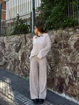 Conjunto de dos piezas de tejido texturizado color beige, compuesto por un buzo de manga larga con cuello polo y un pantalón de corte recto y holgado.