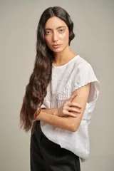 Blusa blanca de lino con cuello redondo, mangas cortas y canesú con alforzas en el frente.
