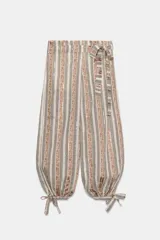 Pantalón bombacho de tiro medio con estampado de rayas verticales en tonos tierra y beige. Presenta aplicación de lentejuelas, cinturón del mismo tejido, forro interior tipo shorts y bajo acabado en puño con lazada. Cierre lateral con cremallera oculta.