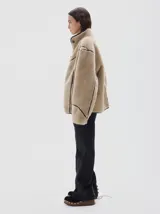 Campera de pelo sintético en color azul, con cuello alto y cierre frontal de botones. Presenta detalles de terminación en cuero vegano color bordó en los bordes, costuras y solapas.