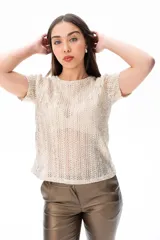 Blusa color dorado de tejido calado con mangas cortas y cuello redondo.