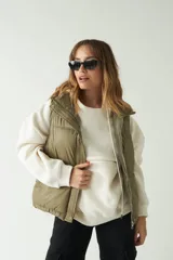 Chaleco puffer color verde oliva con cuello alto y cierre frontal con cremallera.