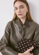 Chaqueta Sabi de cuero sintético en color verde militar, con cuello camisero, cierre frontal con botones y bolsillos de parche delanteros.