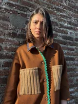 Camisa marrón con cuello, cierre frontal con botones, dos bolsillos frontales y detalles de lentejuelas.