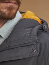 Campera de abrigo azul marino con capucha, cierre frontal con botones y cremallera, múltiples bolsillos y forro interior naranja.